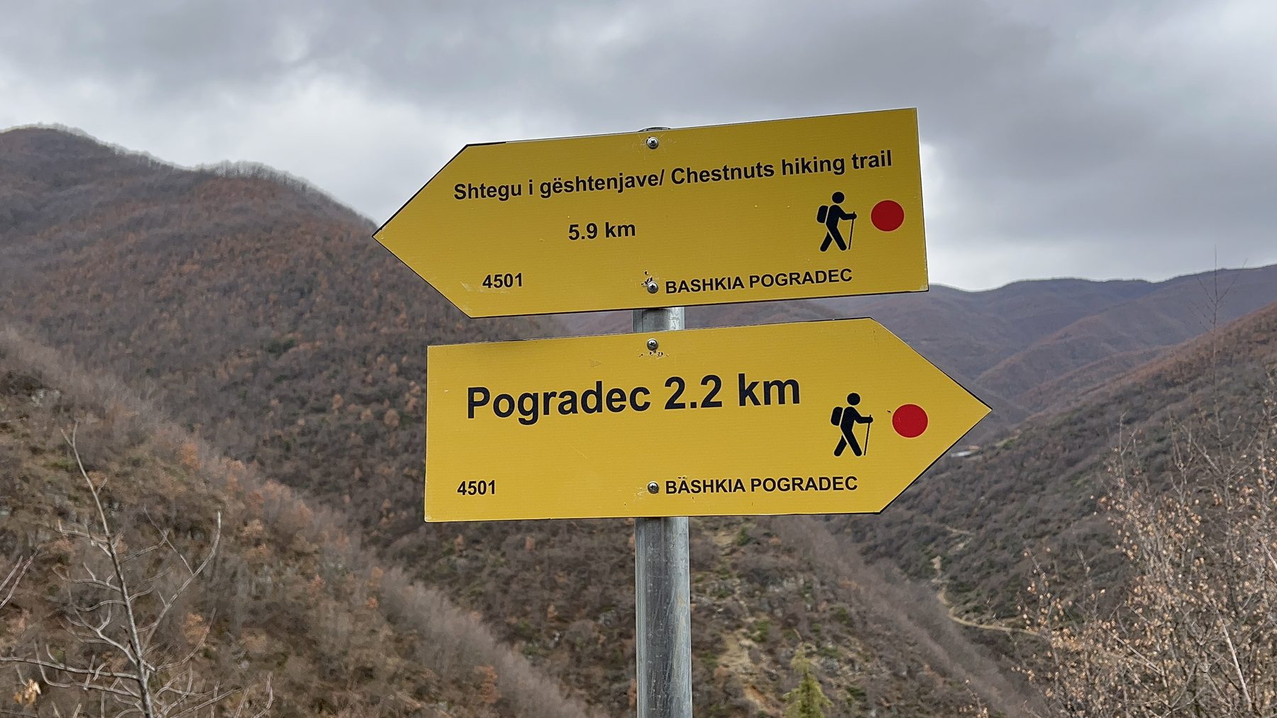 A trail sign near Kisha Shën e Diela church showing 2 km back to Pogradec